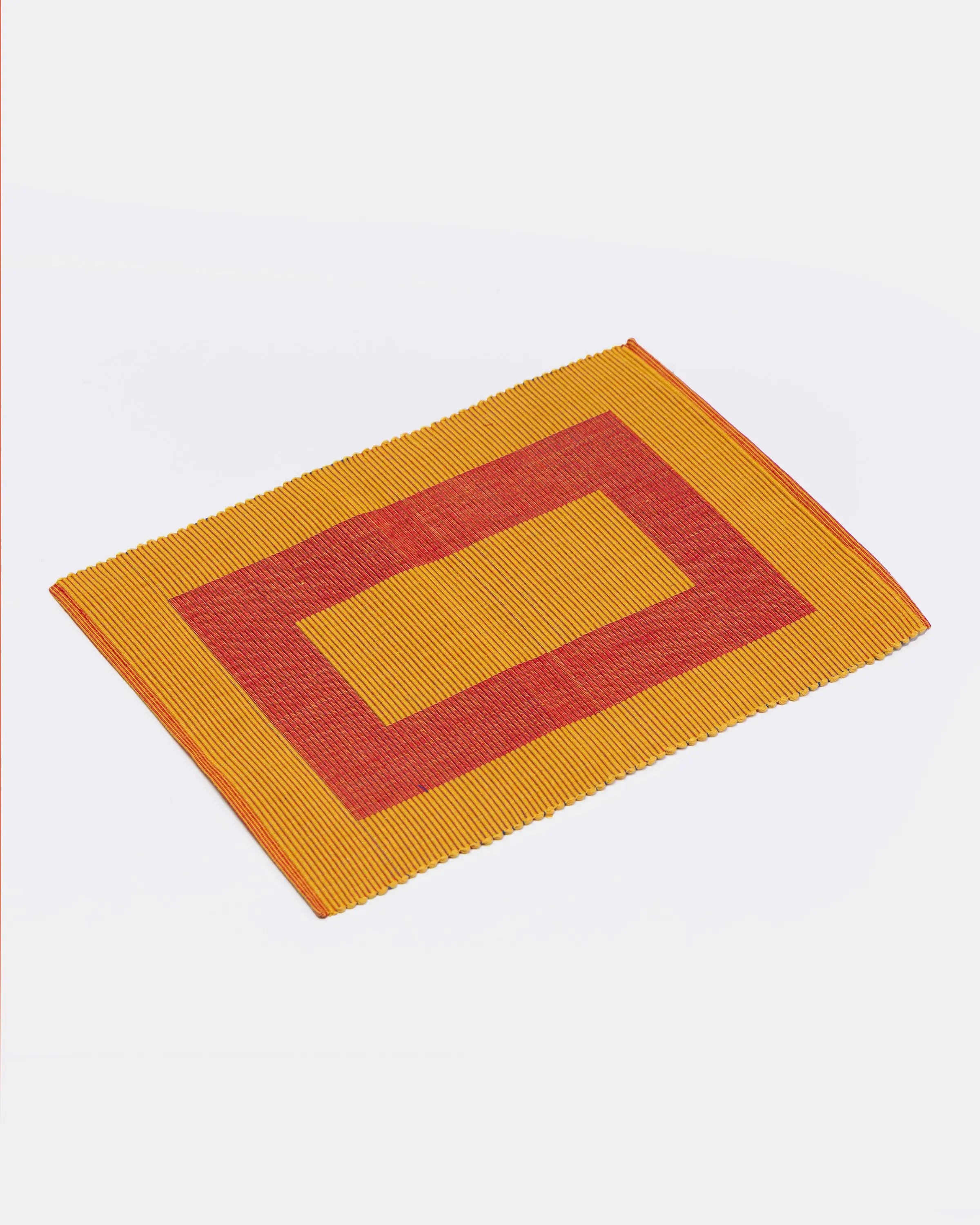 Rectangular placemat with red and yellow pattern on a white background