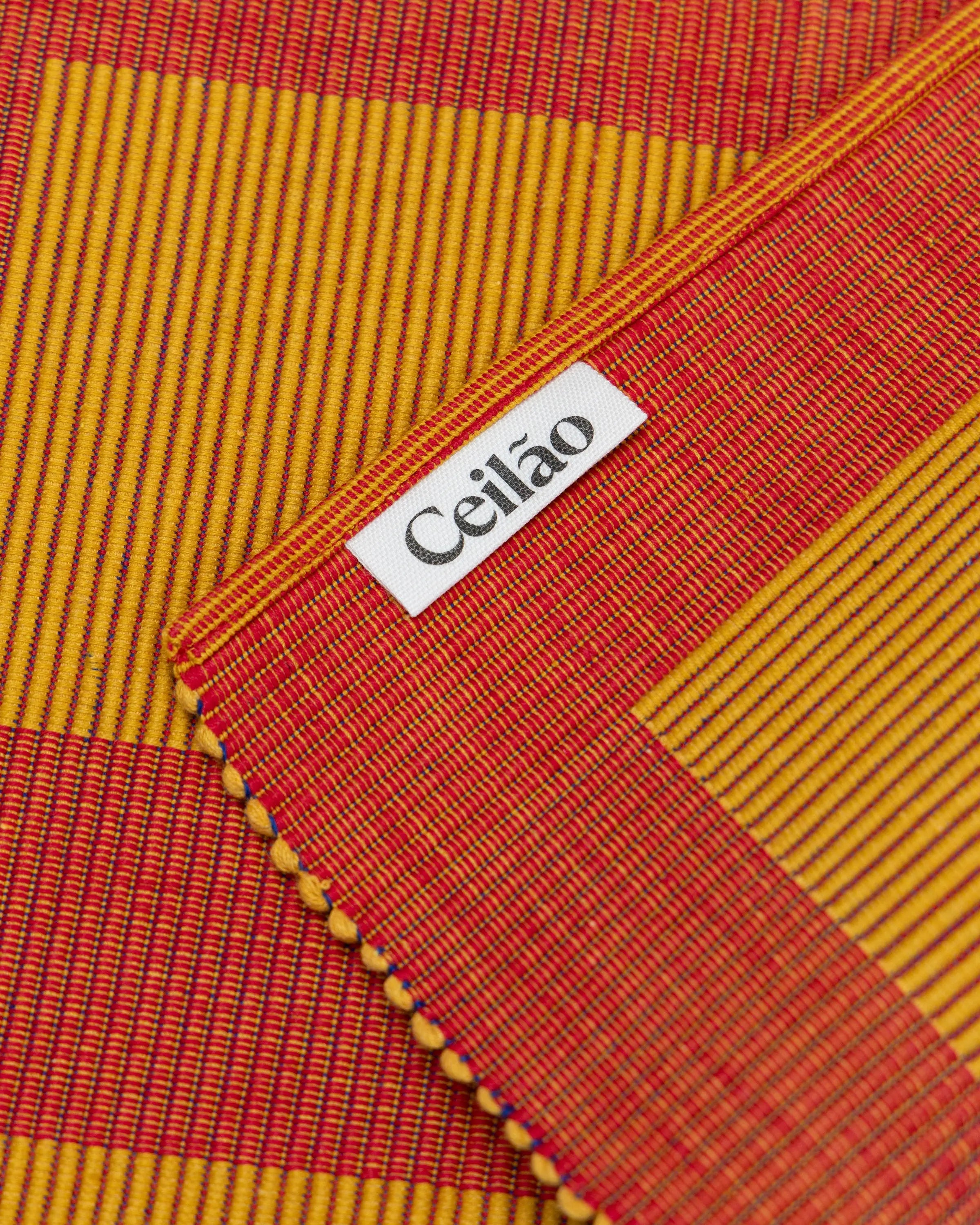 Close-up of a woven fabric with red and yellow stripes and a 'Ceiláo' label.
