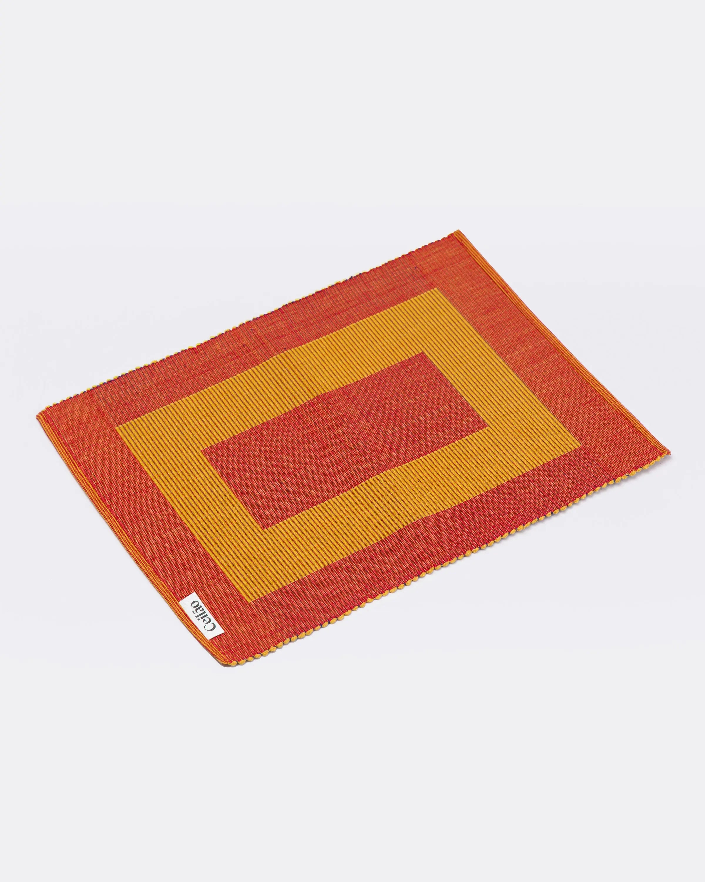 Reversible handmade placemat with red and yellow pattern on a white background