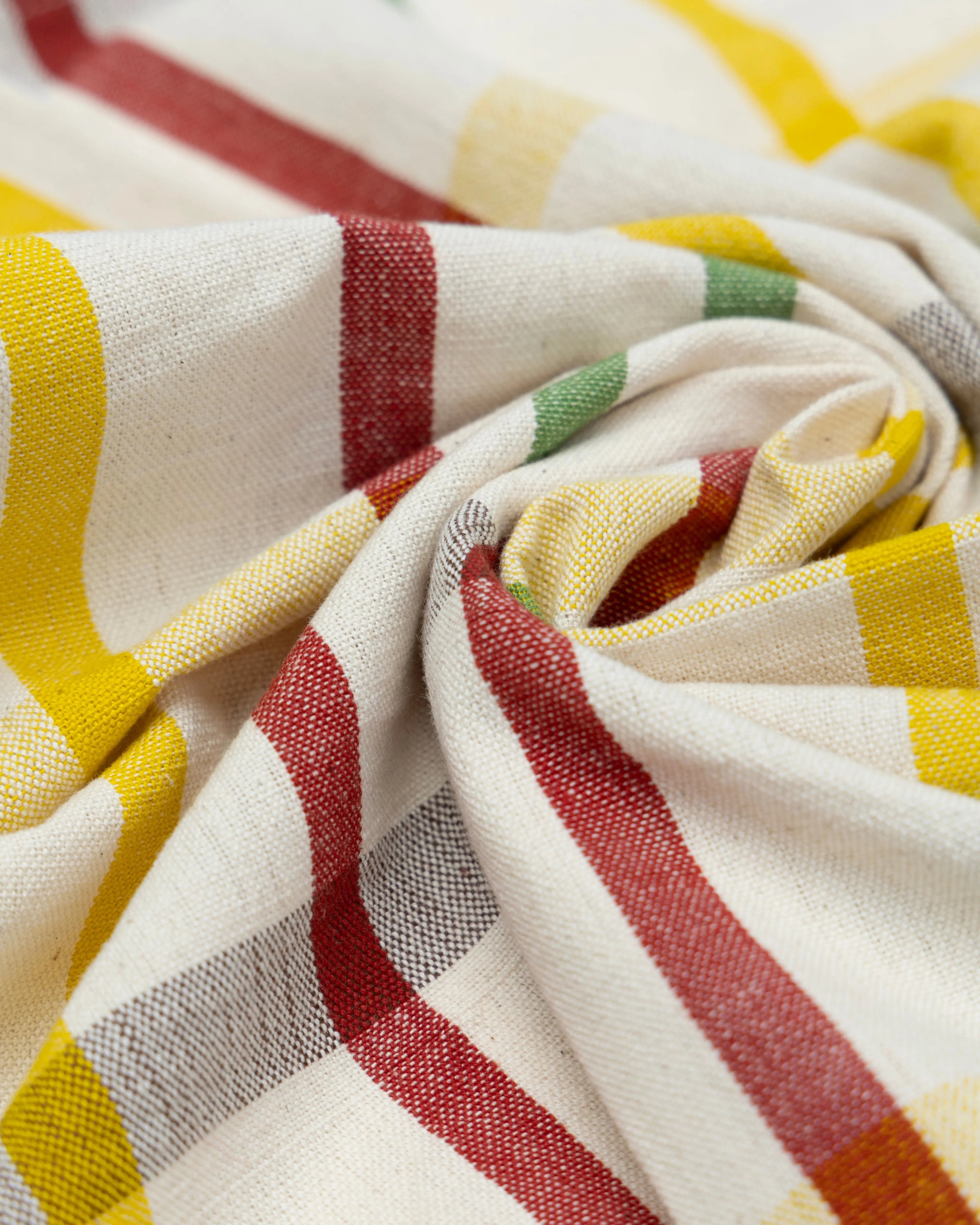 Close-up of handmade tea towel with red, yellow, and green stripes on a white background