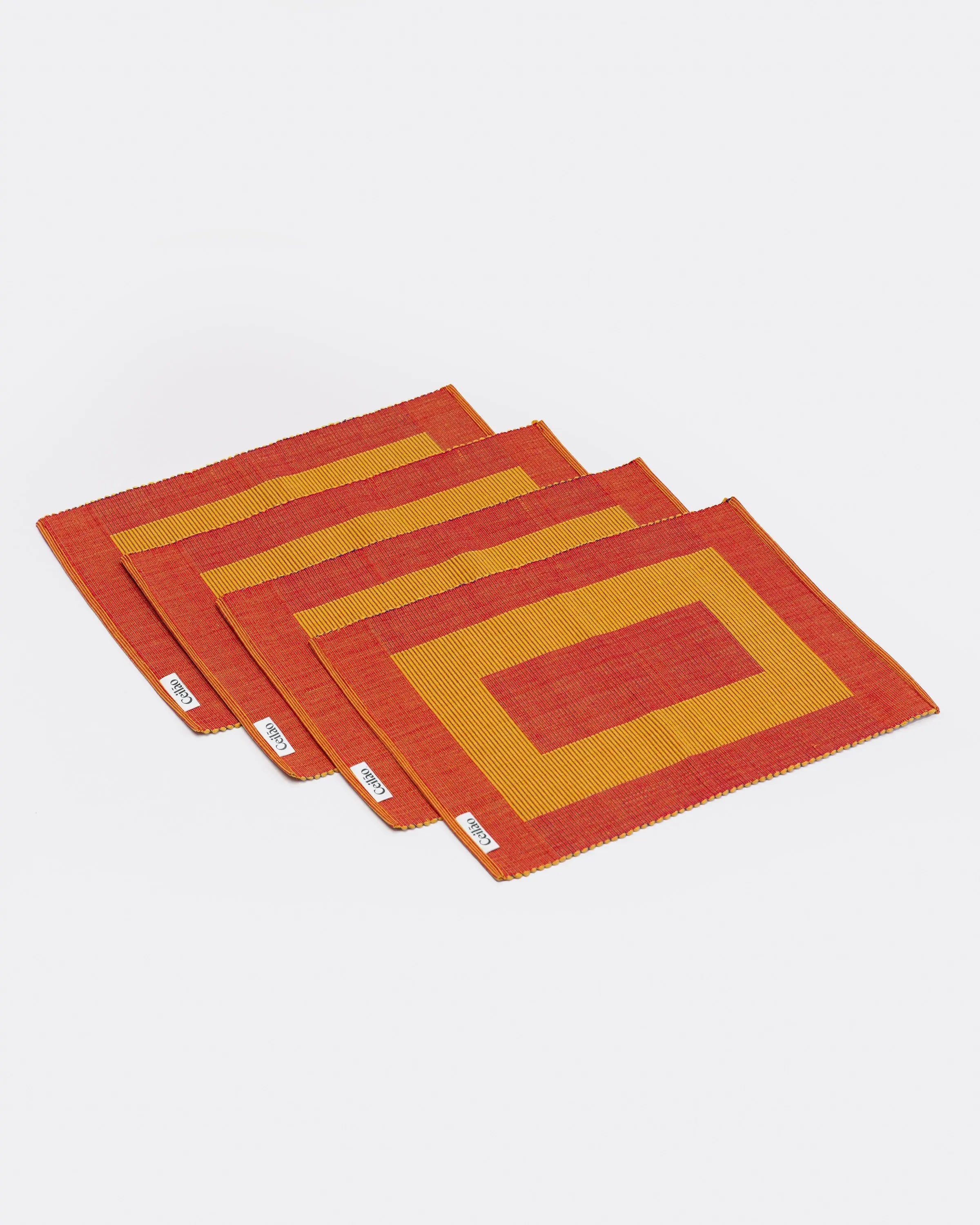 Set of four red and yellow placemats on a white background
