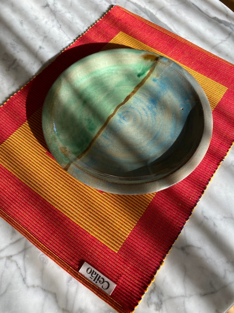 Ceramic bowl on red and yellow handmade cotton placemat with 'Ceilao' branding